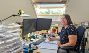 Mitarbeiterin von RWS Gebäudeservice am Schreibtisch zwischen Papierbergen