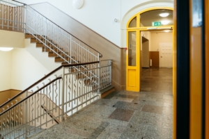 Schulflur mit Treppenhaus und gelbem Eingang
