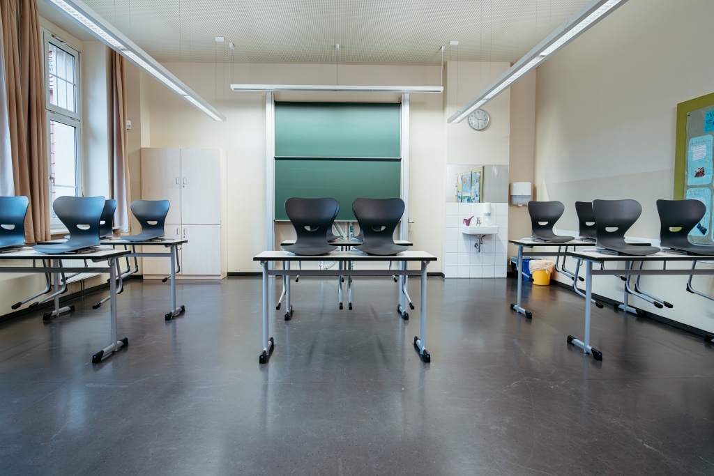 Klassenzimmer mit Tafeln, Stühlen und Waschbecken