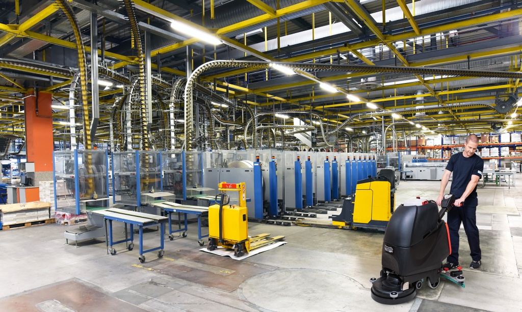 Mitarbeiter des RWS Gebäudeservice reinigt mit einer Bodenreinigungsmaschine eine Produktionshalle.