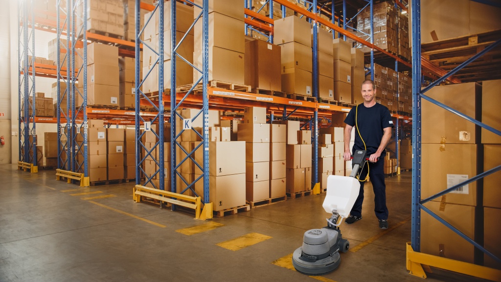 Mitarbeiter des RWS Gebäudeservice reinigt mit einer Maschine die Böden in einem Großhandelslager.