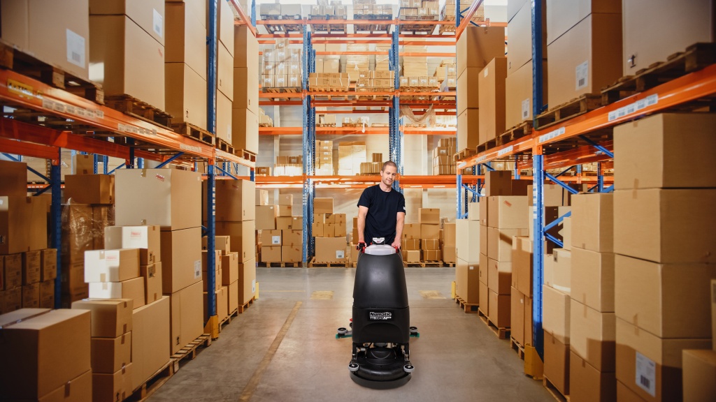 Mitarbeiter des RWS Gebäudeservice reinigt mit einer Maschine die Böden in einem Großhandelslager.