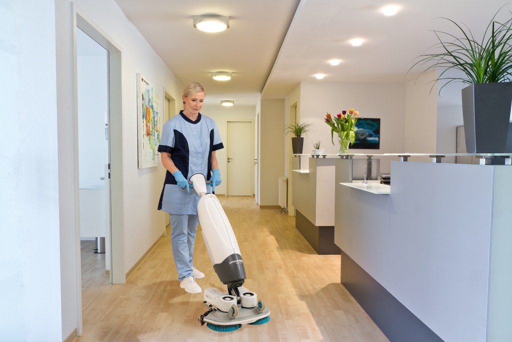 RWS Gebäudeservice Mitarbeiterin reinigt Praxisflur mit moderner i-Mop Maschine für hygienische Sauberkeit.